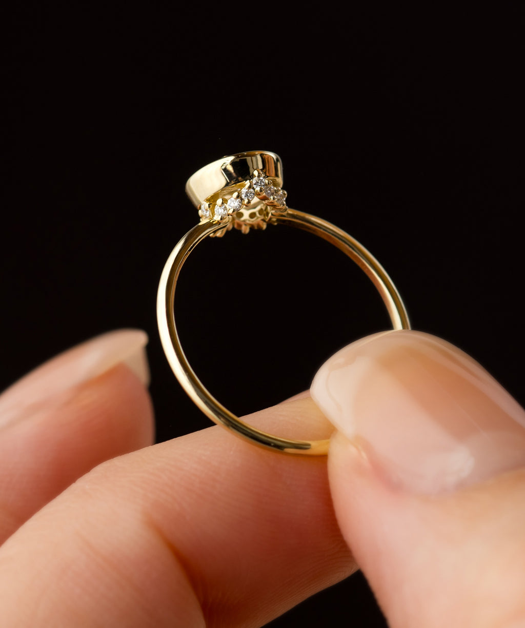 Photo shows someone holding a Melanie Casey Bezel Engagement Ring in Yellow Gold and showing the hidden diamond details underneath.