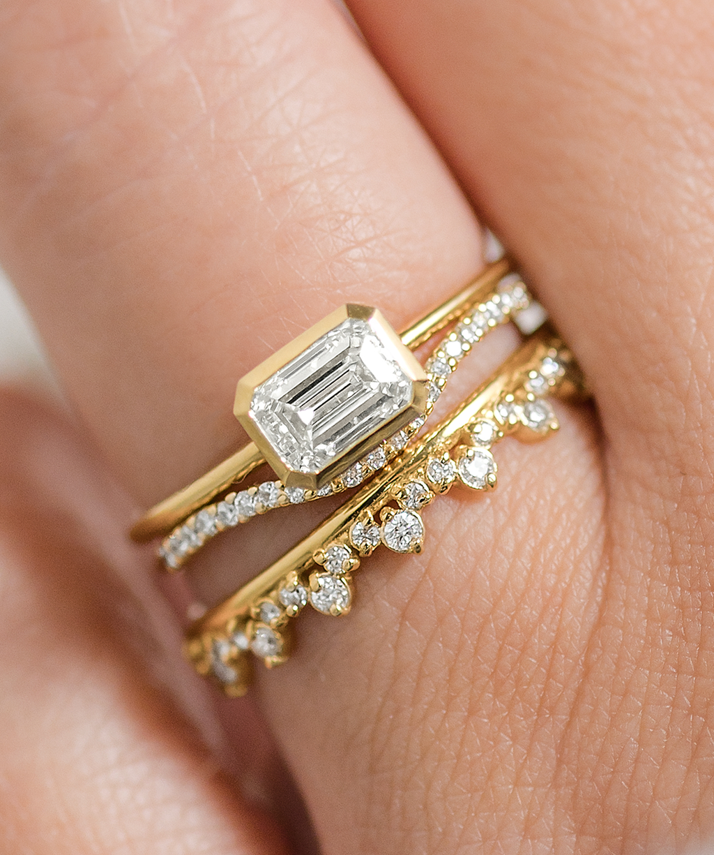 Photo features a model wearing a ring stack featuring the Construct Bezel Set Engagement Ring in Yellow Gold.