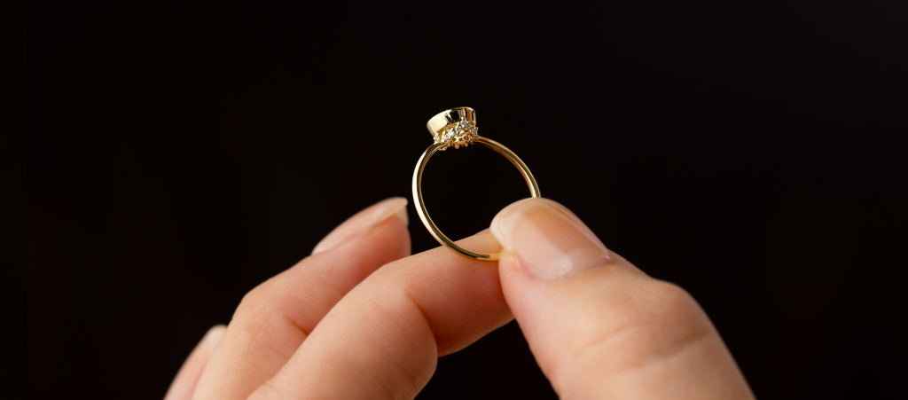 Photo shows someone holding a Melanie Casey Bezel Engagement Ring in Yellow Gold and showing the hidden diamond details underneath.