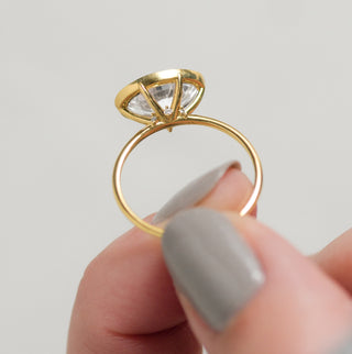 Photo features the Melanie Casey Formation Bezel Ring being held up by a model between two fingers.