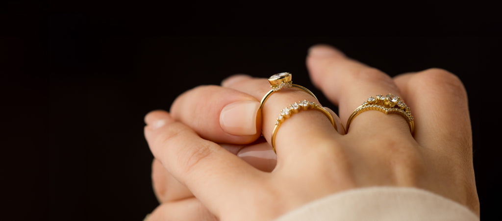 Photo shows a model touching a Caldera Bezel Bezel Engagement Ring on her ring finger and showing off the hidden diamonds underneath.