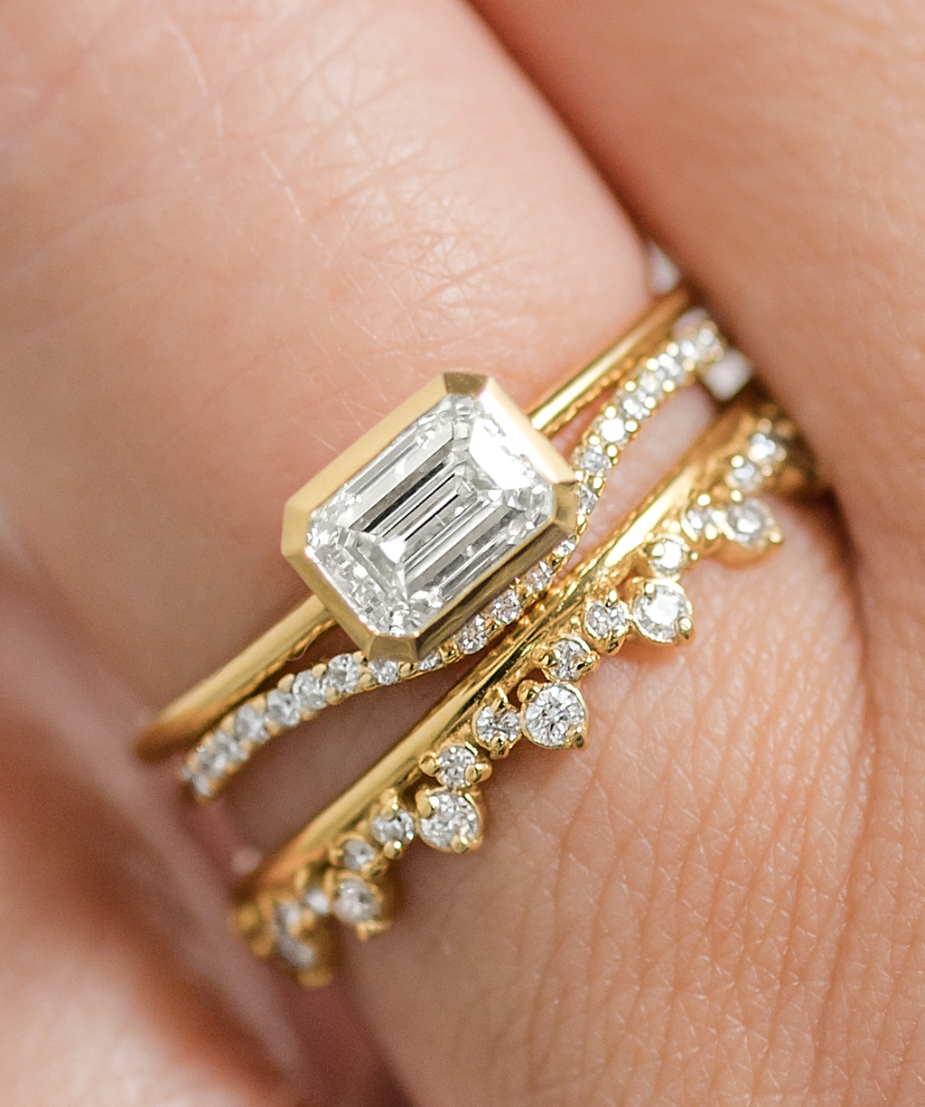 Photo features a model wearing a ring stack featuring the Construct Bezel Set Engagement Ring in Yellow Gold.